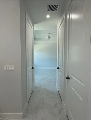 Corridor with marble finish floor, baseboards, visible vents, and recessed lighting