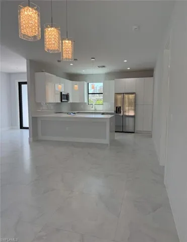 Kitchen featuring marble finish floor, white cabinetry, appliances with stainless steel finishes, and light countertops