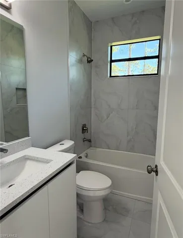 Full bathroom featuring shower / washtub combination, marble finish floor, vanity, and toilet