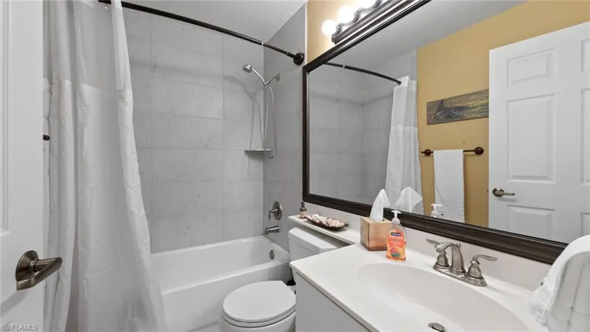 Bathroom with shower / bath combination with curtain, toilet, and vanity