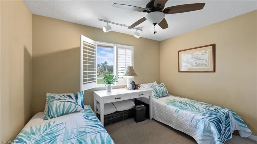 Carpeted bedroom featuring rail lighting, a textured ceiling, and a ceiling fan