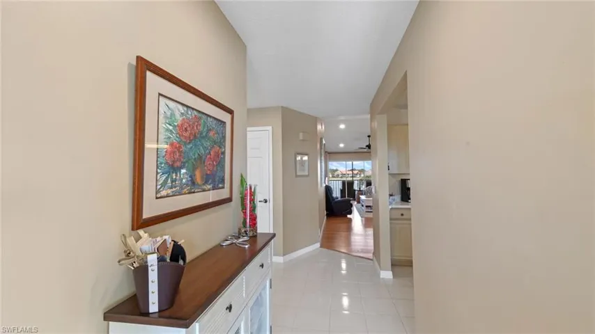 Hall with light tile patterned flooring and baseboards