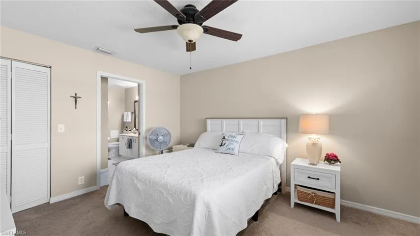 Bedroom with light carpet, baseboards, connected bathroom, a closet, and a ceiling fan