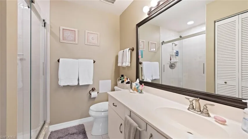 Bathroom featuring a shower stall, vanity, tile patterned flooring, toilet, and baseboards