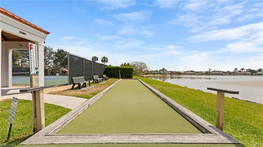 View of community with a bocce ball area, a water view, and a yard