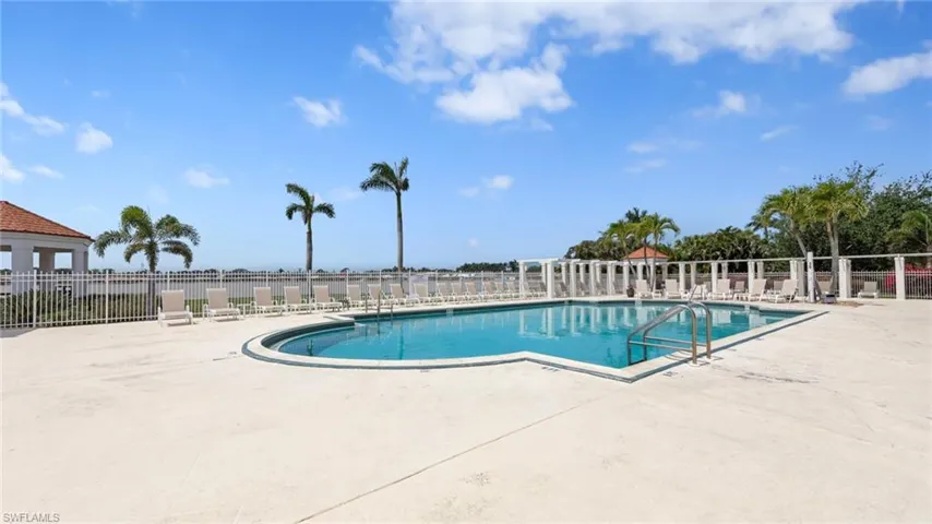 Community pool with a patio area and fence
