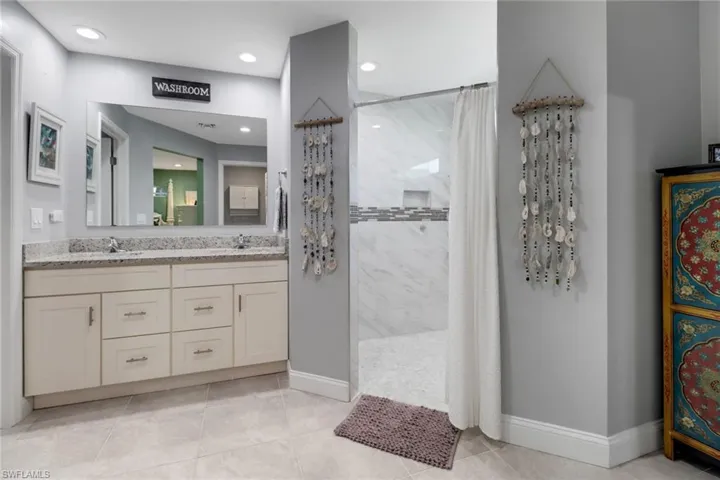 Bathroom with vanity, tile patterned floors, and a shower with shower curtain