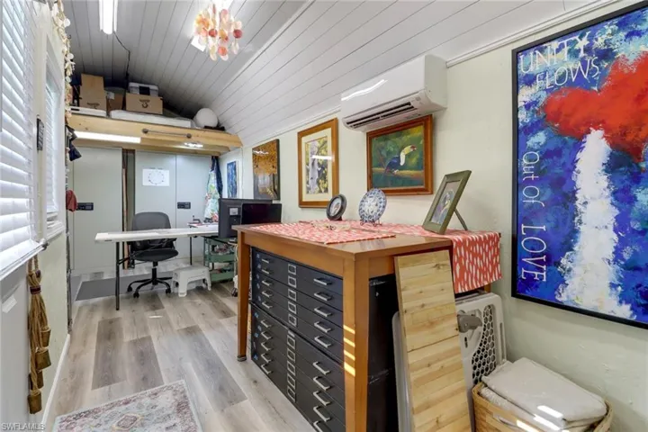 Office area featuring hardwood / wood-style floors, wooden ceiling, vaulted ceiling, a wall mounted air conditioner, and plenty of natural light