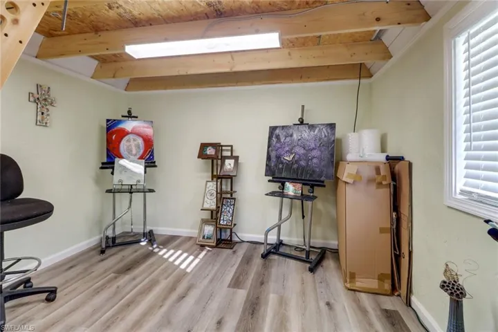 Miscellaneous room with crown molding, a healthy amount of sunlight, beam ceiling, and light wood-type flooring