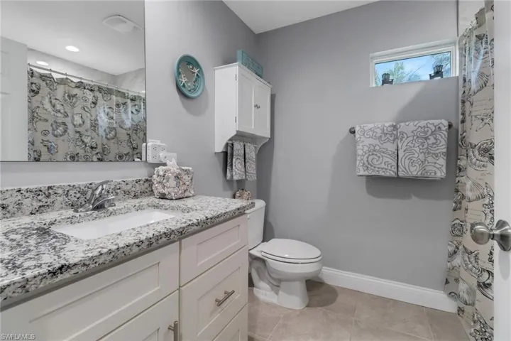 Bathroom with vanity, toilet, curtained shower, and tile patterned flooring
