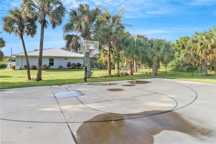 View of sport court with a lawn