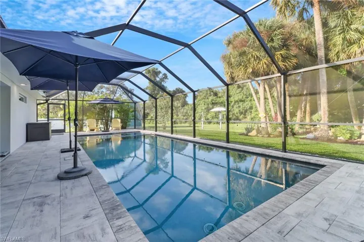View of swimming pool with a patio area, a yard, and glass enclosure