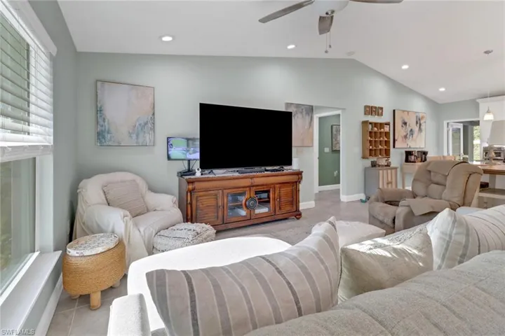 Tiled living room with ceiling fan, a healthy amount of sunlight, and vaulted ceiling