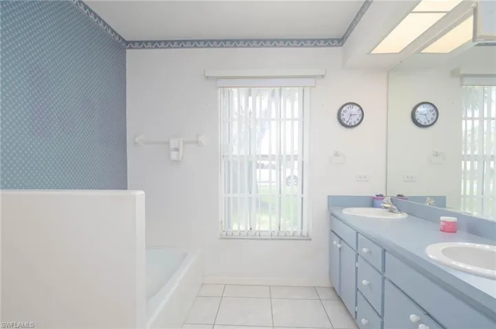Bathroom featuring tile patterned flooring, dual vanity, and a wealth of natural light