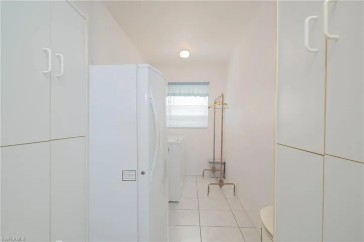 Hall with washer / clothes dryer and light tile patterned floors