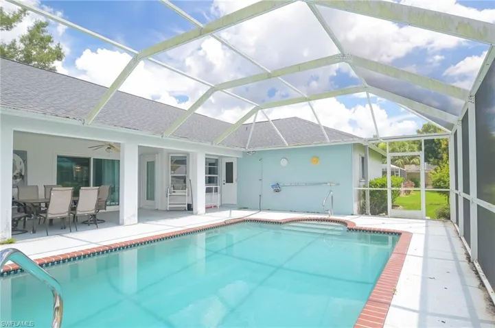 View of swimming pool featuring a patio area, ceiling fan, and glass enclosure