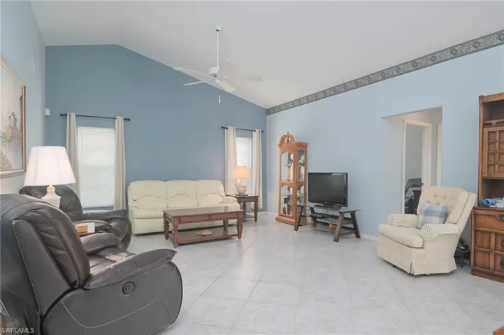Tiled living room featuring high vaulted ceiling and ceiling fan
