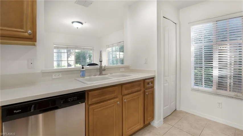 Kitchen with brown cabinetry, stainless steel dishwasher, and plenty of natural light