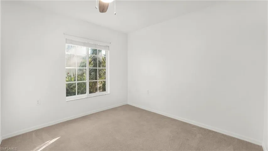Carpeted empty room featuring baseboards and ceiling fan