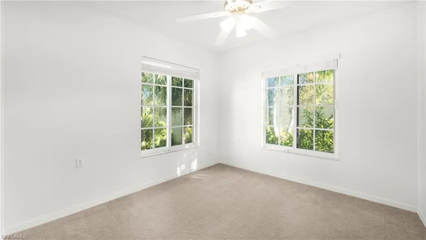 Carpeted spare room with healthy amount of natural light and a ceiling fan