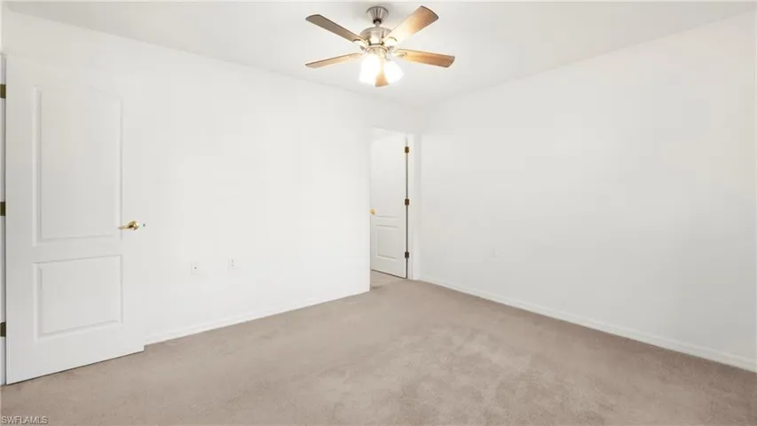 Carpeted empty room featuring baseboards and a ceiling fan