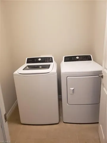 Washroom with light tile patterned floors and independent washer and dryer
