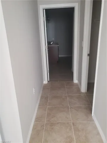 Hall featuring baseboards and light tile patterned floors