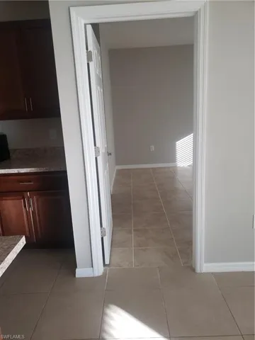 Hall with baseboards and light tile patterned floors