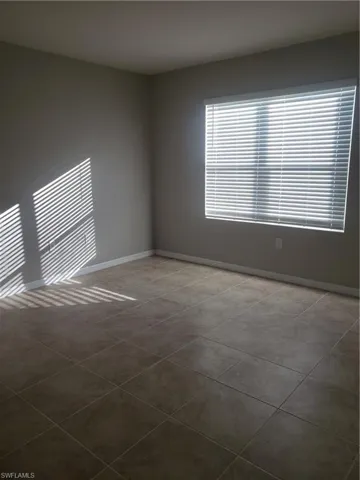 Tiled empty room featuring baseboards
