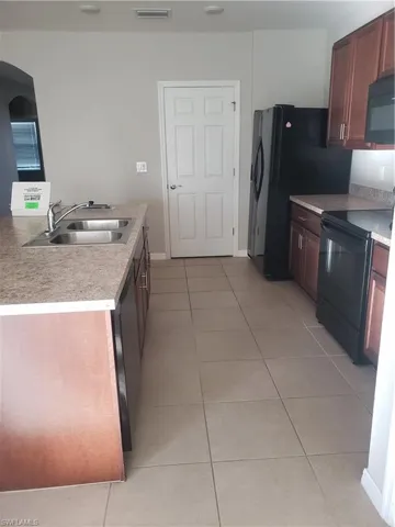 Kitchen with range, light tile patterned floors, light countertops, and dishwasher