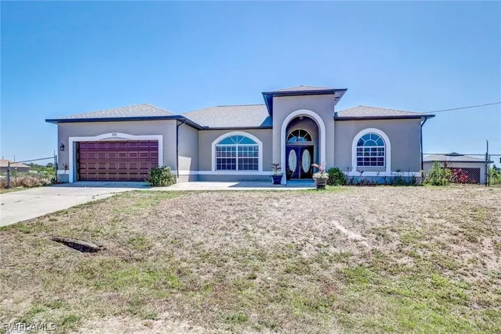 View of front of property featuring stucco siding, concrete driveway, a garage, and french doors