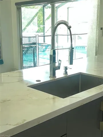 Kitchen view of light stone counters and dark cabinetry