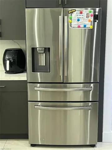 Kitchen with stainless steel refrigerator with ice dispenser, light countertops, and light tile patterned flooring