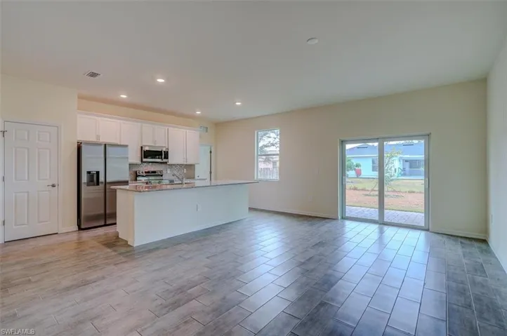 Kitchen featuring white cabinetry, tasteful backsplash, an island with sink, appliances with stainless steel finishes, and light wood-type flooring