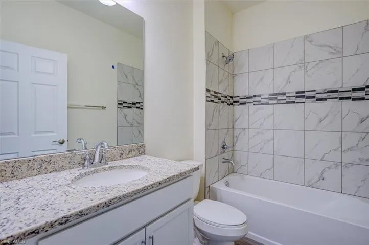 Full bathroom featuring vanity, toilet, and tiled shower / bath combo