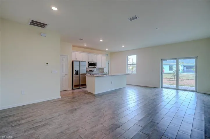 Kitchen featuring white cabinets, light wood-tile flooring, a kitchen island with sink, and appliances with stainless steel finishes