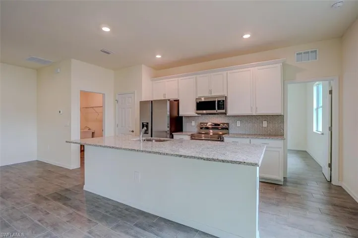 Kitchen featuring white cabinetry, a kitchen island with sink, light hardwood / wood-style flooring, and stainless steel appliances