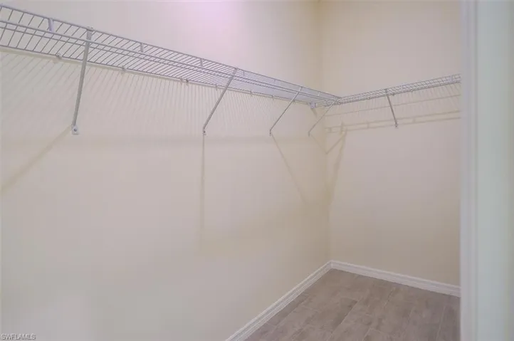 Walk in closet with wood-type flooring