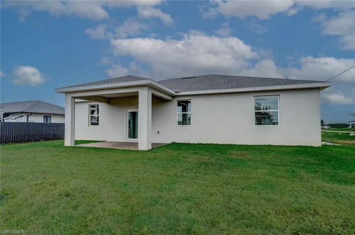 Back of house featuring a lawn and a patio area