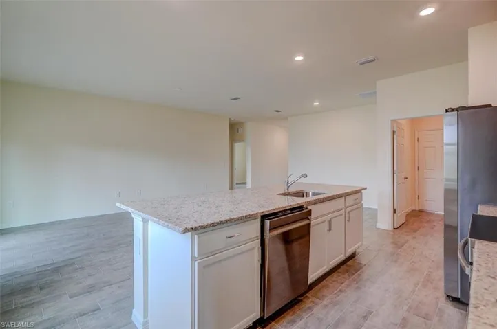 Kitchen featuring stainless steel appliances, sink, a center island with sink, light hardwood / wood-style flooring, and white cabinets