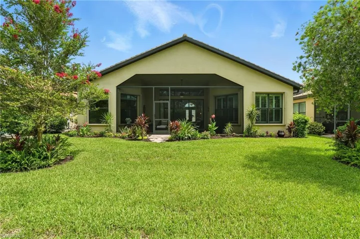 Rear view of property with stucco siding, a lawn, and a sunroom