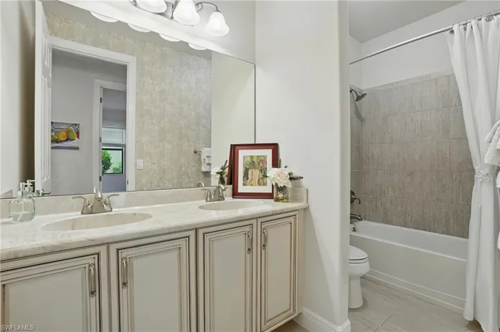 Bathroom featuring double vanity, shower / bathtub combination with curtain, and tile patterned floors
