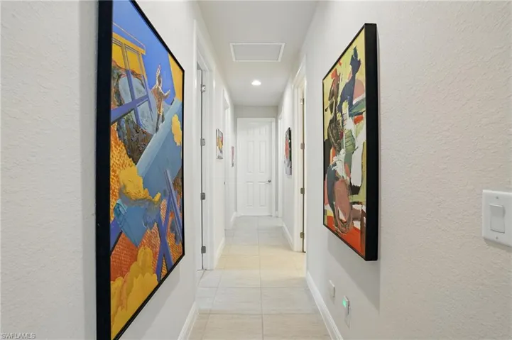 Hall featuring light tile patterned floors, a textured wall, and recessed lighting