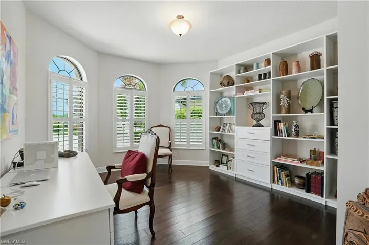 Home office with healthy amount of natural light and dark wood-type flooring