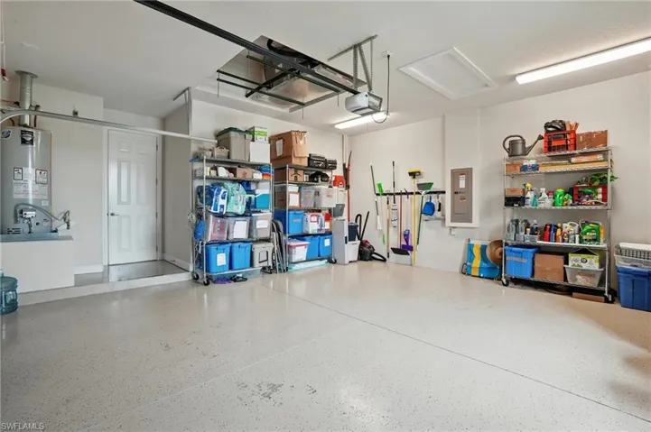 Garage with gas water heater, a garage door opener, and electric panel