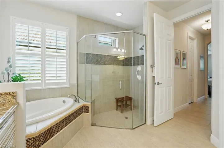 Full bath featuring a garden tub, a stall shower, vanity, and tile patterned flooring