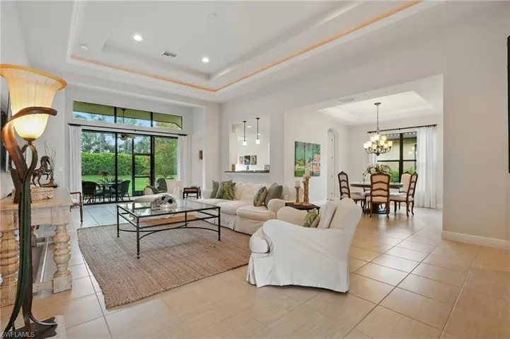 Living room featuring a raised ceiling, light tile patterned floors, a chandelier, and recessed lighting