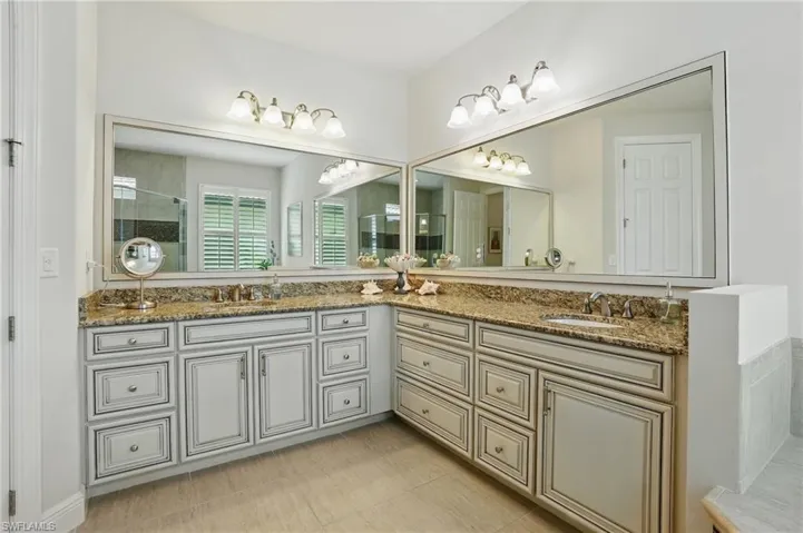 Full bath featuring double vanity and tiled shower