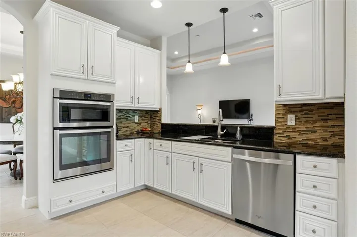 Kitchen with appliances with stainless steel finishes, white cabinets, backsplash, recessed lighting, and decorative light fixtures