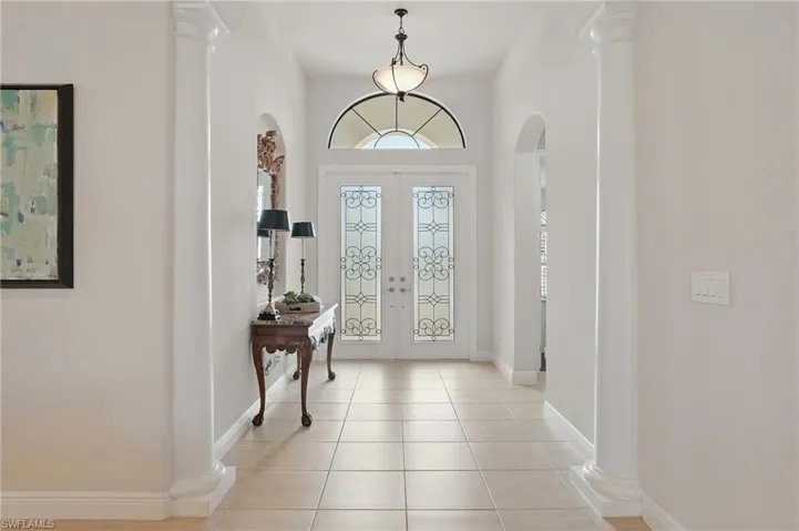 Foyer entrance featuring arched walkways, light tile patterned flooring, french doors, and ornate columns